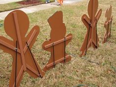 three wooden sculptures sitting on top of a grass covered field