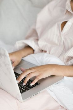 a woman laying in bed using a laptop computer