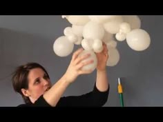 a woman is holding up some white balloons