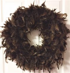 a wreath made out of feathers hanging on a door handle with a light in the background