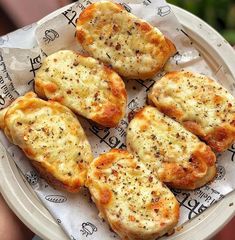 four pieces of bread sitting on top of a white paper plate covered in cheese and seasoning