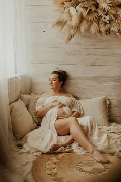 a woman sitting on top of a bed in a white dress