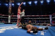 a man laying on the ground in front of a referee with his arm raised up