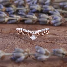 a close up of a ring on top of a piece of wood with lavender flowers in the background