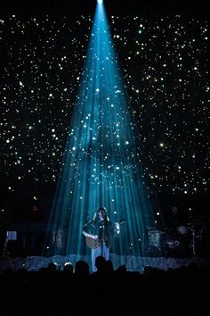 a person standing on a stage in front of a light show with bright blue lights