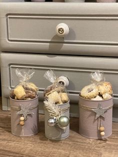 three tin canisters filled with cookies on top of a wooden floor next to a dresser