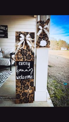 a door hanger that says every sunny welcome is decorated with ribbon and bows on the front porch