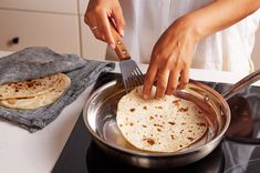 a woman is using a fork to make tortillas