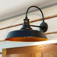 a black and gold light hanging from the side of a wooden wall next to a window