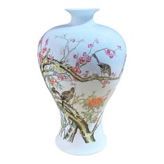 a white vase with birds and flowers painted on the front, sitting against a white background