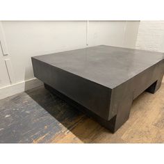 a black coffee table sitting on top of a wooden floor next to a white brick wall