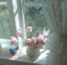 pink flowers in a white vase on a window sill next to a blue bird