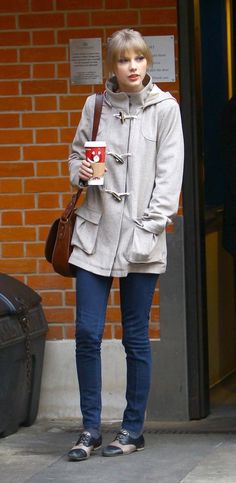 a woman standing on the sidewalk holding a coffee cup