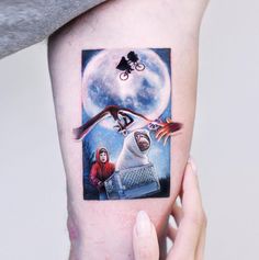 a person with a tattoo on their arm holding up a piece of art that has an image of a woman riding a bike