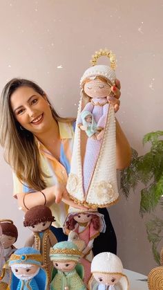 a woman standing next to a group of knitted nativity figurines