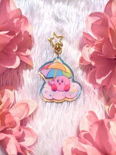 a keychain with an umbrella on top of it and pink flowers in the background