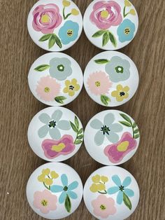 six flowered plates sitting on top of a wooden table