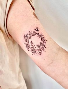 a woman's arm with a tattoo on it that has flowers and leaves in the middle