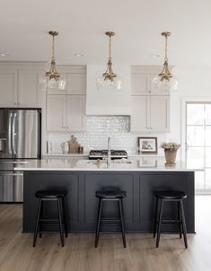 35 Stunning Off-White Kitchen Cabinets For A Spacious Look All White Kitchen With Black Island, Cream And Black Cabinets Kitchen, Cream Cabinets Black Island, Black Island White Kitchen, Moody Kitchen White Cabinets, Black And Off White Kitchen, Urban Bronze Kitchen Island, Black Kitchen White Countertops, Kitchen With Black Fixtures