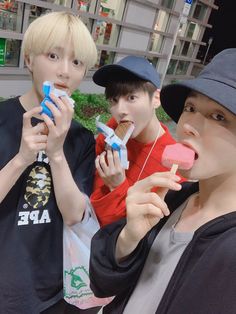 three young men are eating pops and lollipops