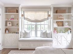 a white bedroom with built in bookshelves and shelves on either side of the window