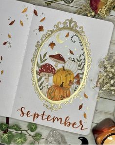 an open notebook with autumn illustrations on it and the words september written in orange ink