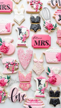 decorated cookies are arranged on a white surface with pink and black accents, such as monogrammed letters