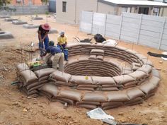 two men are working on a construction project in the middle of a dirt area with cement bags