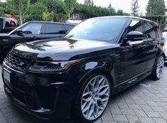 a black range rover parked next to other cars