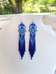 These Beautiful Native American Beaded Earrings are custom made by Elaine out of Blue, White, Turquoise and Silver with blue bugle beads on them.  They are 5 inch long and 1 inch wide with silver ear wires on them, can be changed to post or clips. If you like them and want in another color just let me know I do special orders.  Thanks for looking. Artisan Blue Earrings With Dangling Beads, Artisan Blue Beaded Earrings, Artisan Blue Earrings For Festival, Southwestern Blue Drop Earrings, Southwestern Style Blue Drop Earrings, Southwestern Blue Beaded Earrings With Round Beads, Southwestern Style Blue Earrings For Festivals, Nickel-free Blue Southwestern Earrings, Southwestern Style Blue Festival Earrings