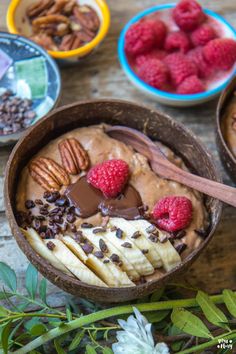 two bowls filled with chocolate, bananas and raspberries on top of a wooden table