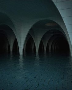 an empty subway station with water in the floor and lights at the end of it