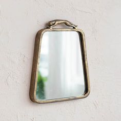 a mirror mounted to the side of a wall with a rope hanging from it's edge