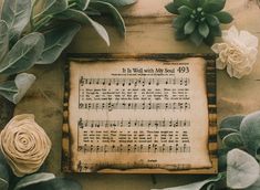 an old sheet music is surrounded by flowers and greenery on a wooden surface with the words it's well written, my soul 945