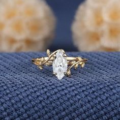 a close up of a gold ring with a white stone in the center on a blue cloth