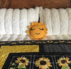 a crocheted sunflower is sitting on the edge of a bed