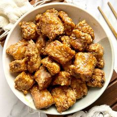 a white bowl filled with meat next to chopsticks