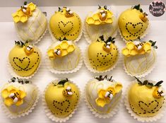 twelve yellow decorated strawberries are arranged in rows on a white surface with black dots