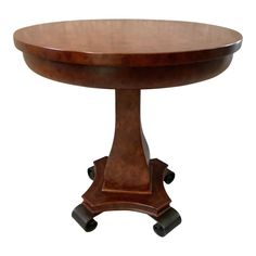 a round wooden table with wheels on the bottom and one leg raised up to it's center