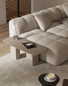 a coffee table sitting on top of a white rug next to a beige sectional couch