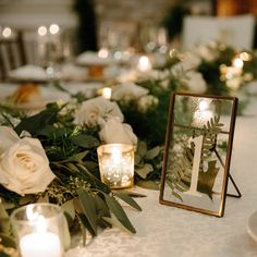 the table is set with candles, flowers and greenery for an elegant wedding reception