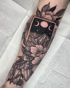 a black and white tattoo on the arm with flowers, stars and moon in it