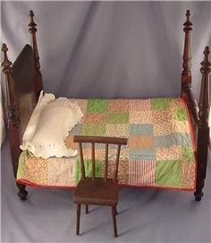 a doll bed with a chair and quilt on it