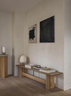 a wooden table with books on top of it in front of a wall mounted painting