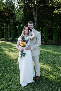 a bride and groom standing in the grass