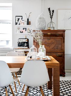 a dining room table with white chairs and black and white checkered floor tiles on the floor