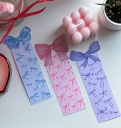 three bookmarks with bows on them next to a potted plant and other items