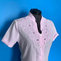 "Today's vintage offering is this classic 1950s embroidered cutwork blouse. This lovely top is constructed from a semi-sheer whisper pink cotton with a beautiful cutwork yoke. This sweet blouse has an embroidered standing collar, an embroidered cutwork bodice, short sleeves with embroidered cuffs, and a scalloped embroidered placket. There's a 4 1/2\" slit on either side from the hemline. This sweetheart closes with four buttons down the center front. Normally, I would swap the buttons to match, Embroidered Cuffs, Cutwork Blouse, Standing Collar, Lovely Tops, Chic Top, Embroidered Shorts, Pink Blouse, Cut Work, Pink Cotton