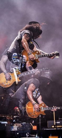 the guitarist is jumping in the air with his guitar and another person behind him on stage