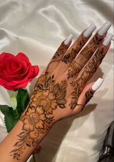 a woman's hand with henna on it next to a rose